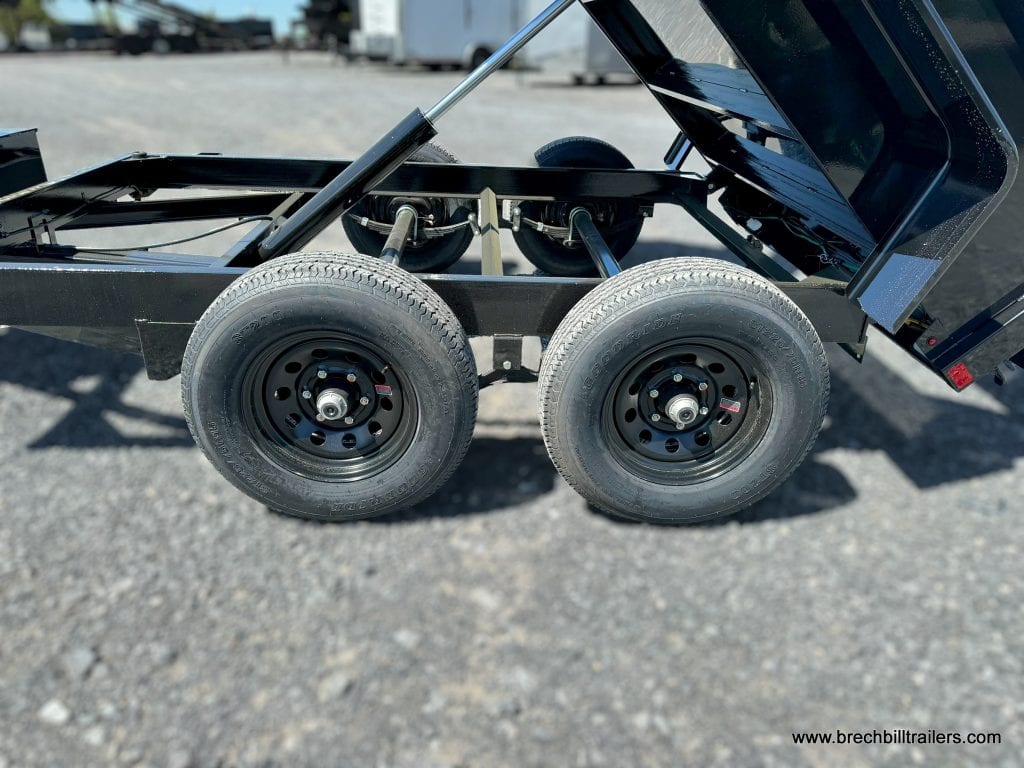 The axles and wheels on a Bwise Light Duty 10K Dump Trailer