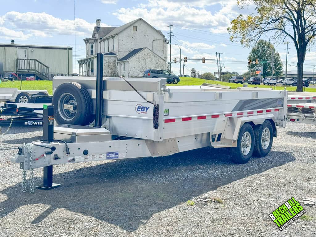 A parked EBY 14K Aluminum Bumper Pull Dump Trailer with a spare wheel mounted.