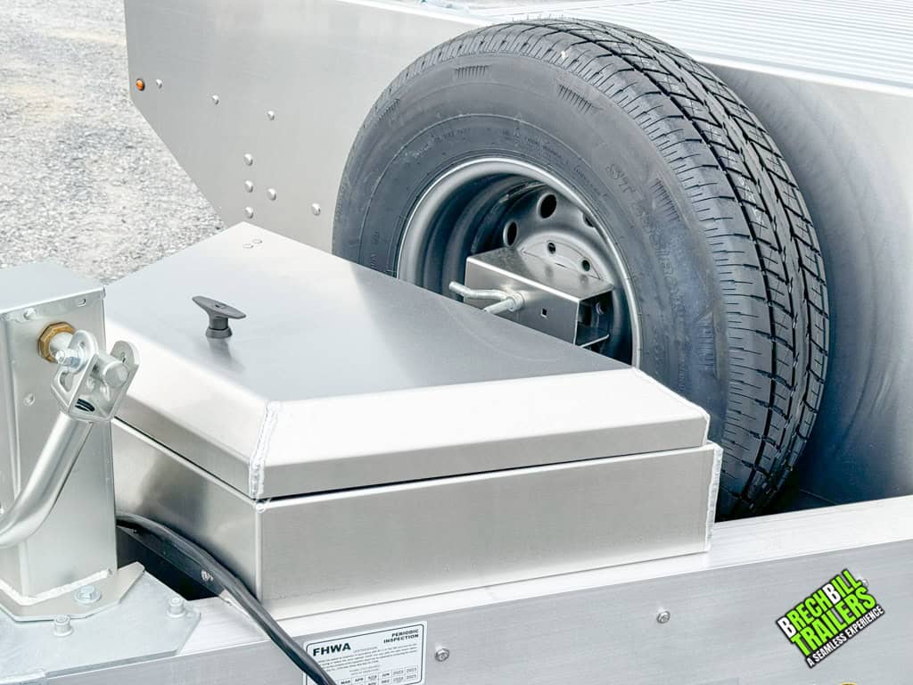 Closed toolbox on the trailer with spare wheel mounted by it.