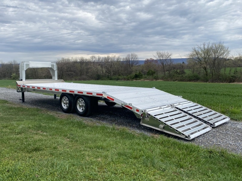 EBY 15.9K Deck-Over Gooseneck Equipment Trailer parked with ramps down.