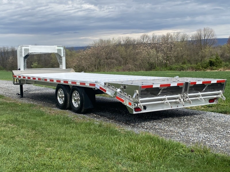 Brand new EBY 15.9K Deck-Over Gooseneck Equipment Trailer parked on a gravel road.