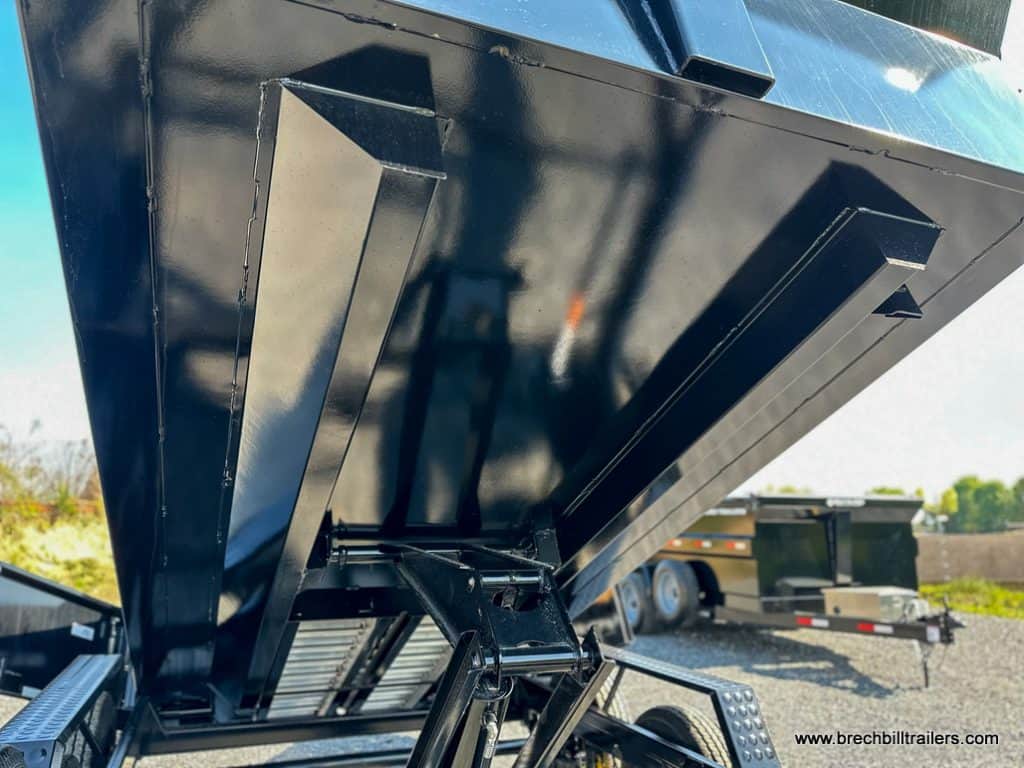 Under the dump bed of the trailer.