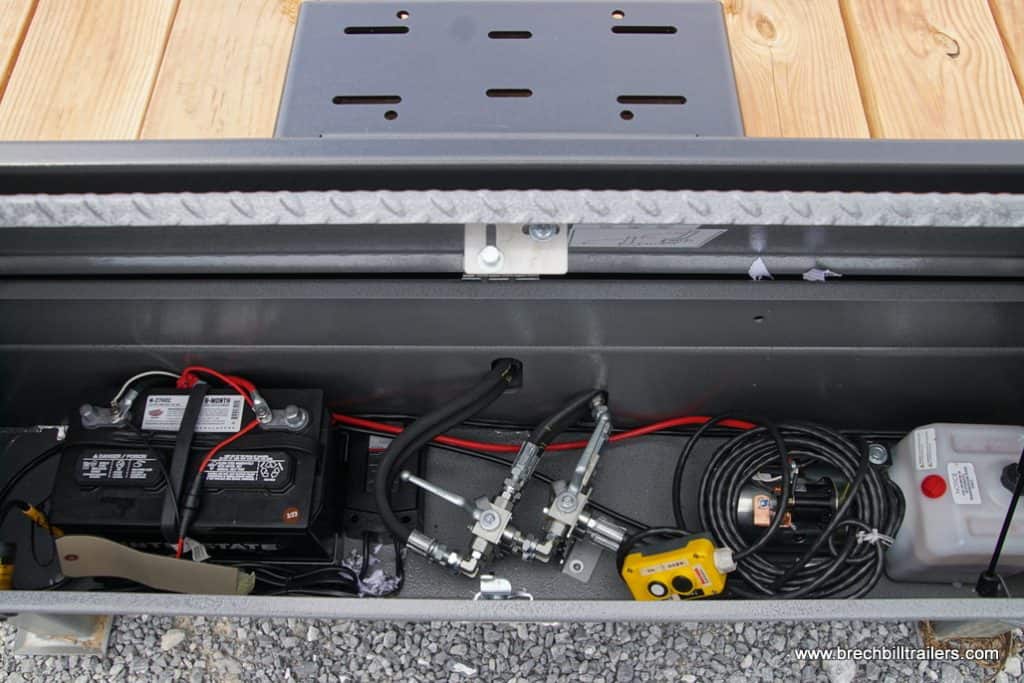 Battery box with hydraulic controls and lines running through it.