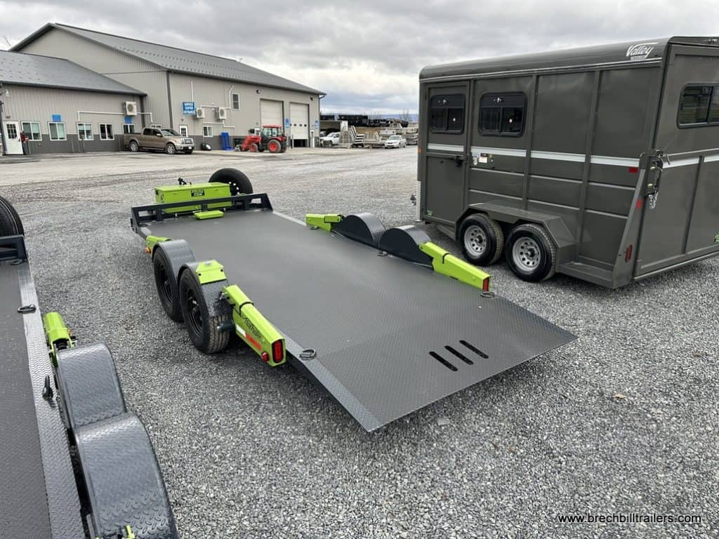 FlatTrak 7x18 Lay Flat 14K Equipment Hauler Trailer parked next to a livestock trailer