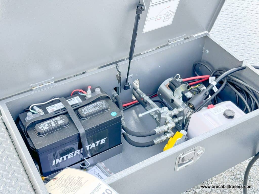 Battery box with power line, fluid reservoir and hydraulic lines running through it.