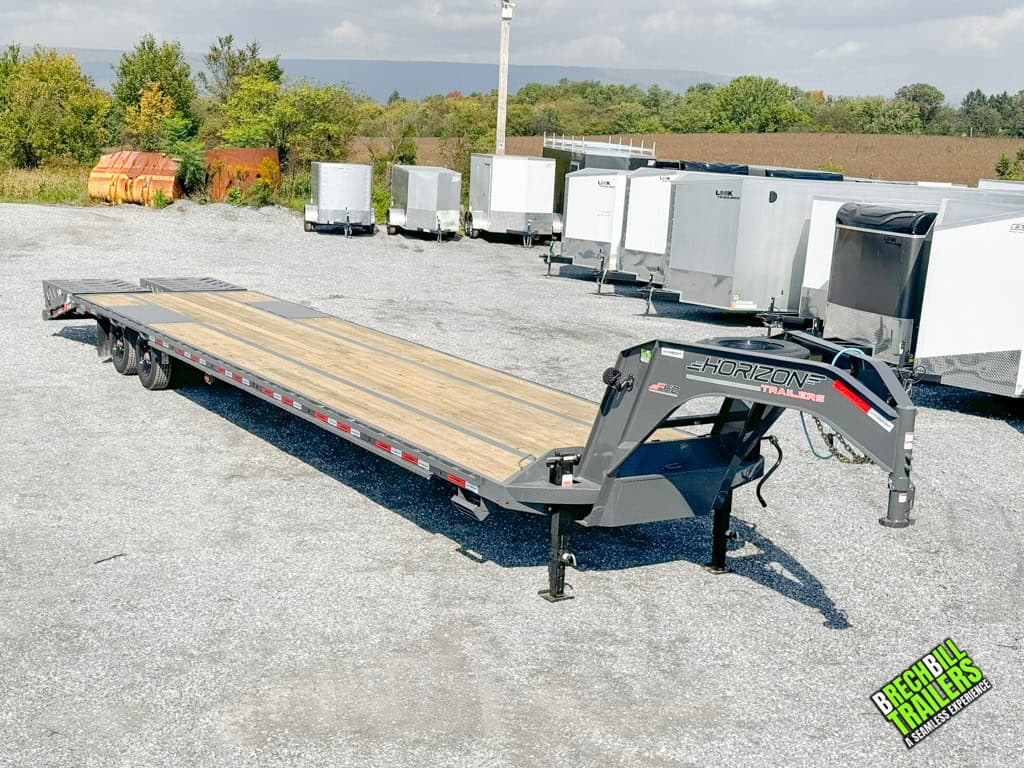 A front view of the Horizon 40ft Flat Deck Gooseneck Trailer surrounded in a lot next to other trailers for sale.