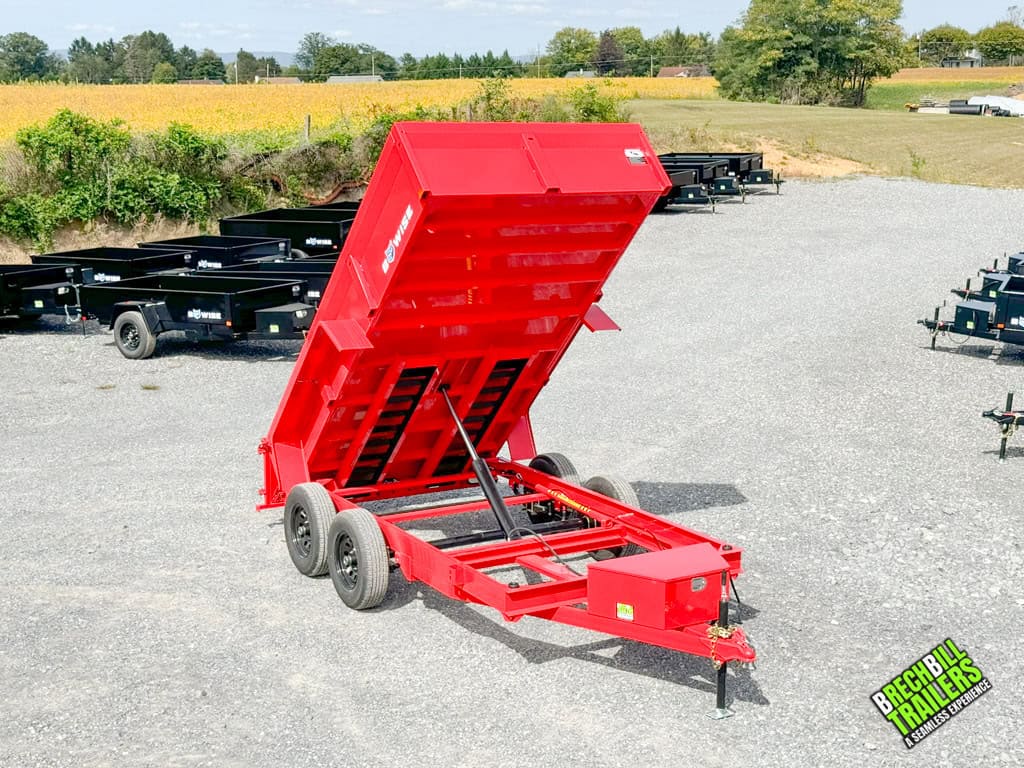 A red Bwise LP LE 10K Low Pro Dump Trailer with the cylinder in view as it extends into the dump position.